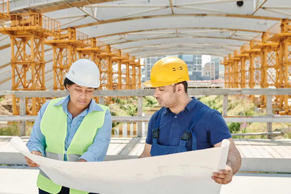 Two construction professionals review plans together at an active job site.